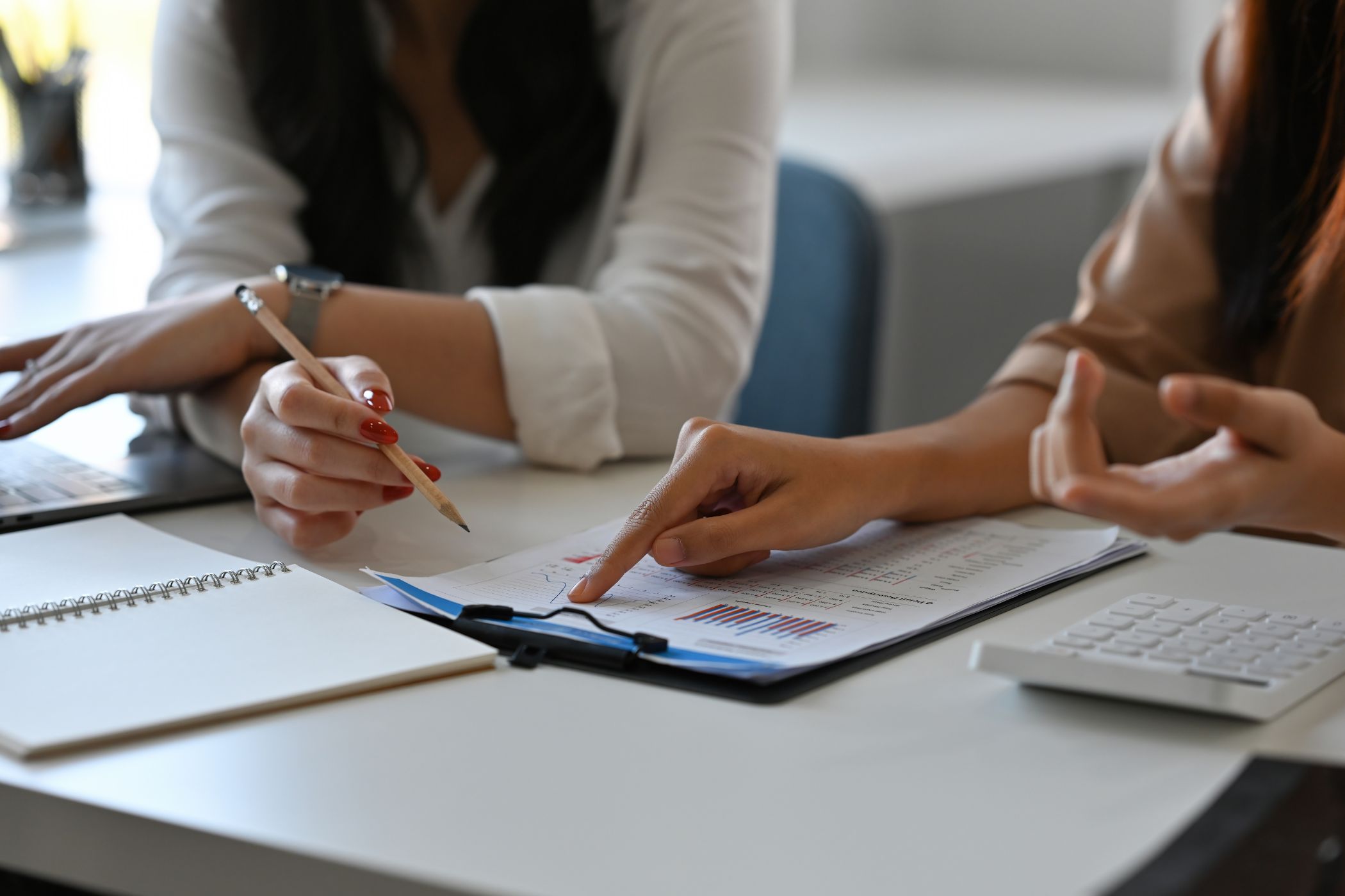 Two people reviewing a printed brief and charts on a clipboard at a desk