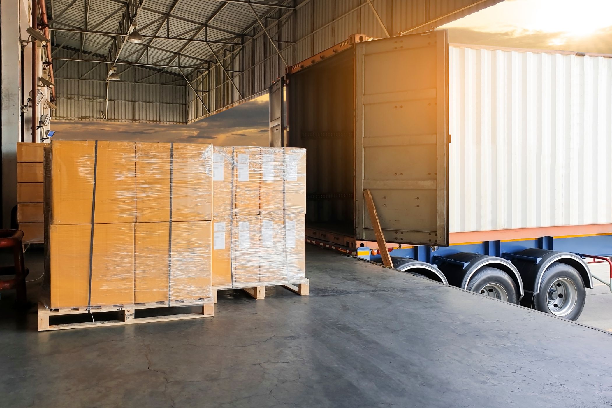 Wrapped pallets of boxed stock ready to load onto a lorry at a loading bay