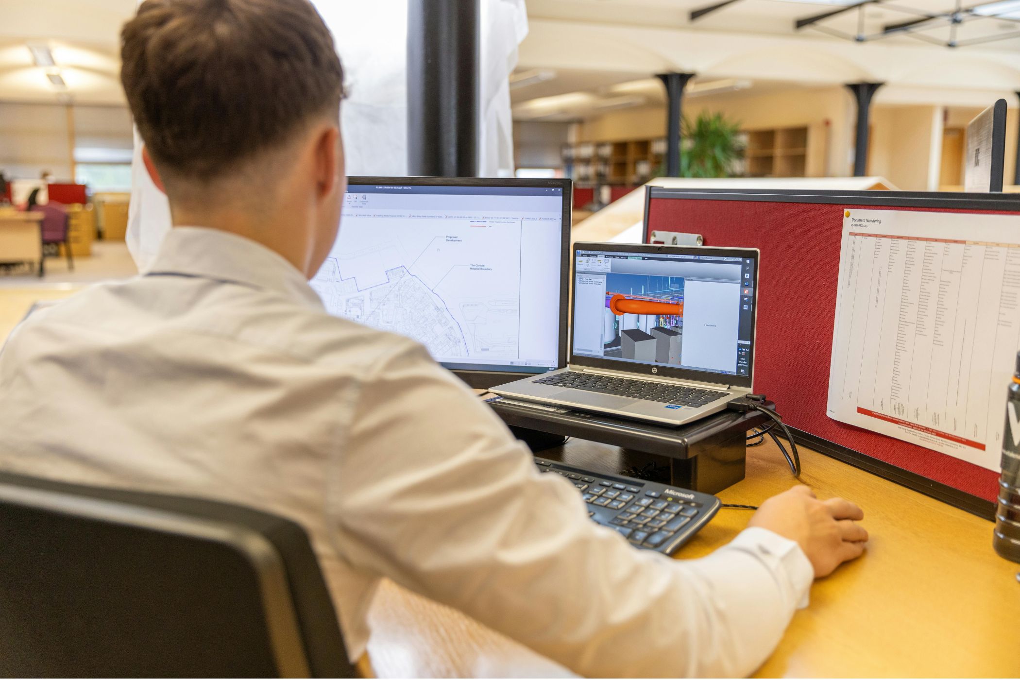 Designer working on a 3D display model across a monitor and laptop